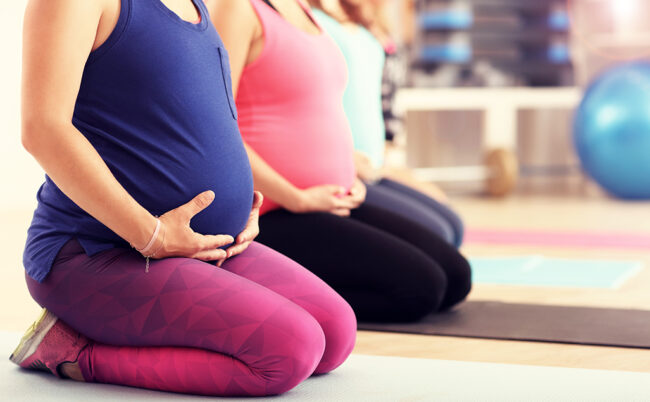 femmes enceintes en tenues de sport assises genoux pliés