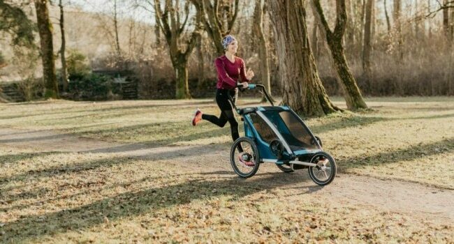 Frau joggt mit Kind durch Park