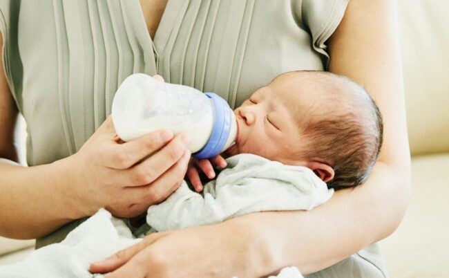 bébé qui boit le biberon avec sa maman
